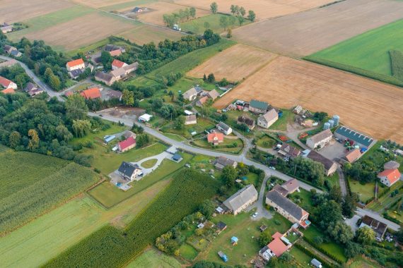 Widok z lotu ptaka na niewielką wieś w Polsce - domy ustawione wzdłuż głównej drogi